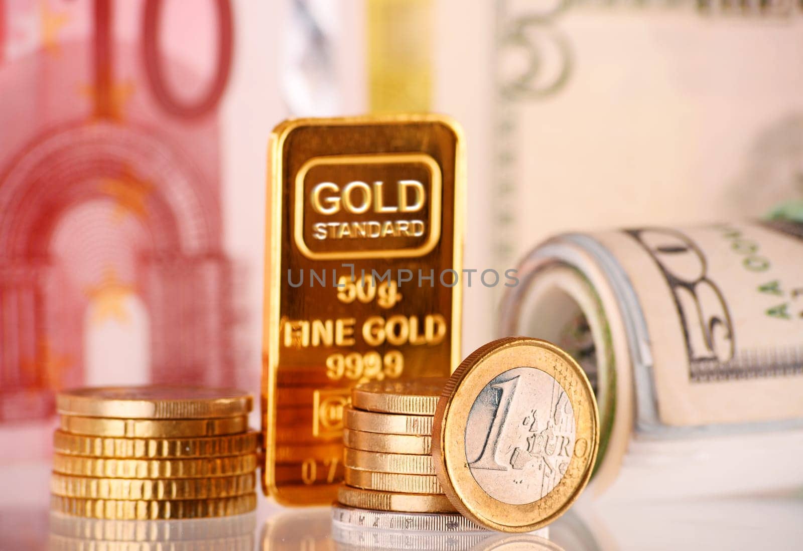 Composition with 50 gram gold bar, banknotes and coins.