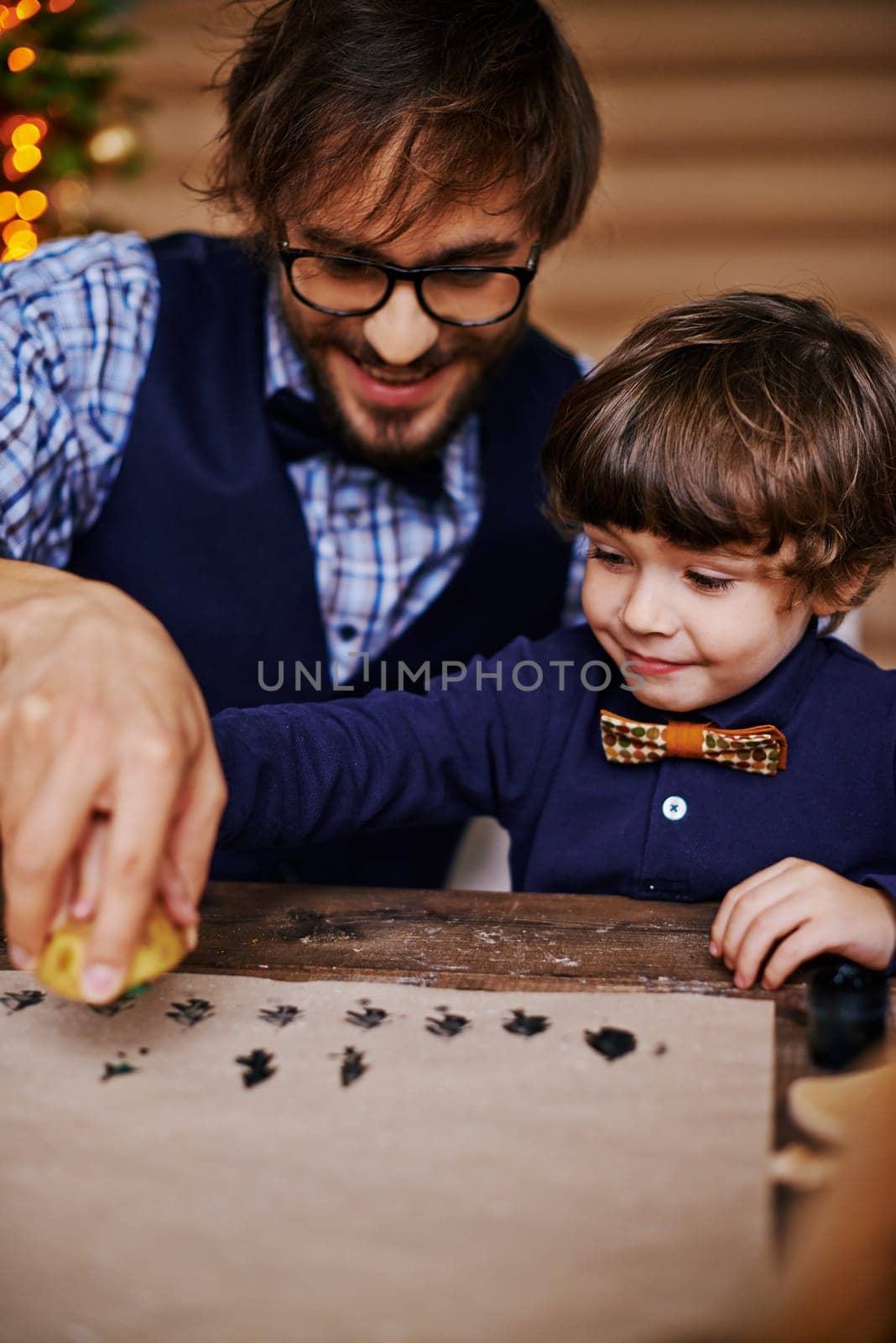Young man and cute little boy printing firtree shapes on paper