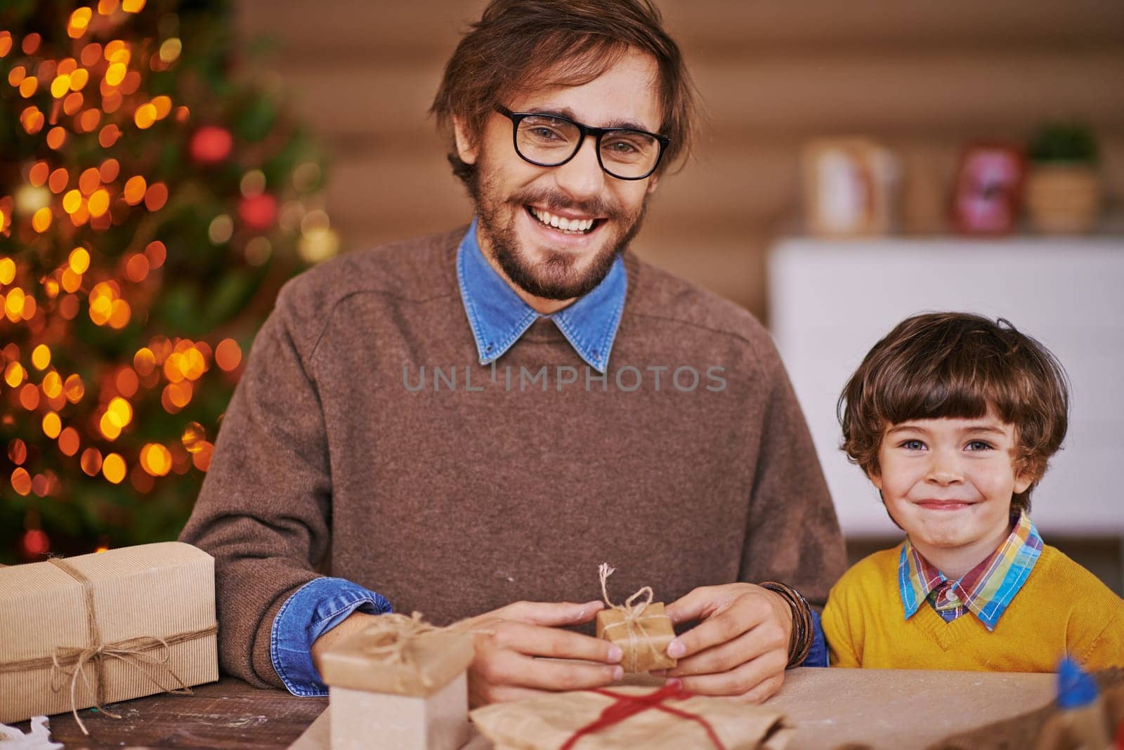 Happy young man and his son with wrapped gifts looking at camera and smiling