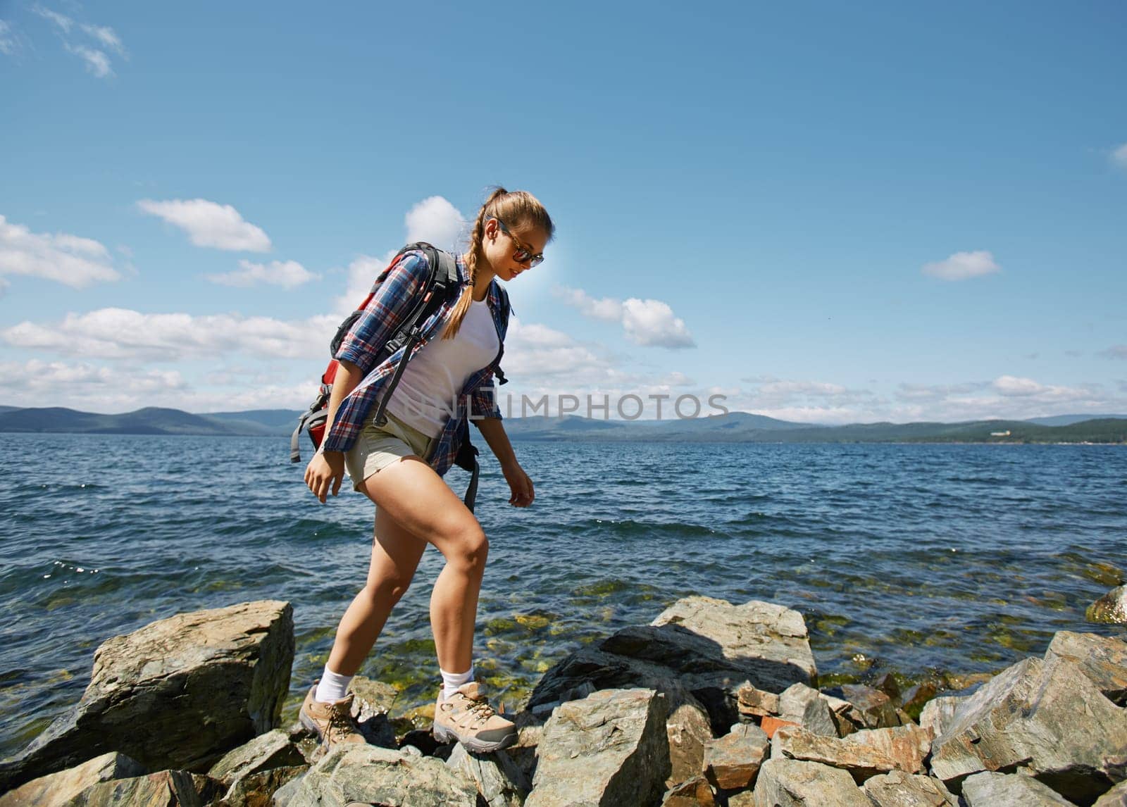 Pretty hiker walking on rocks by the seaside