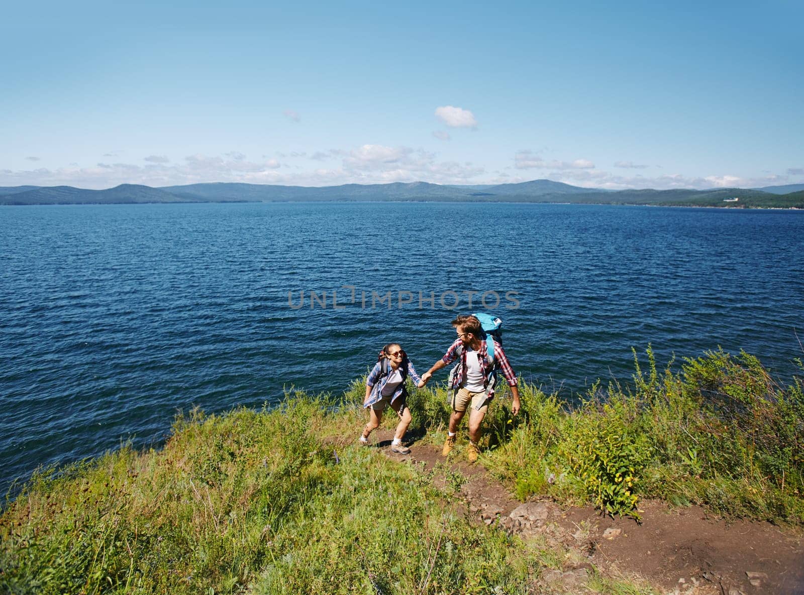 Amorous travelers hiking by the seaside in summer