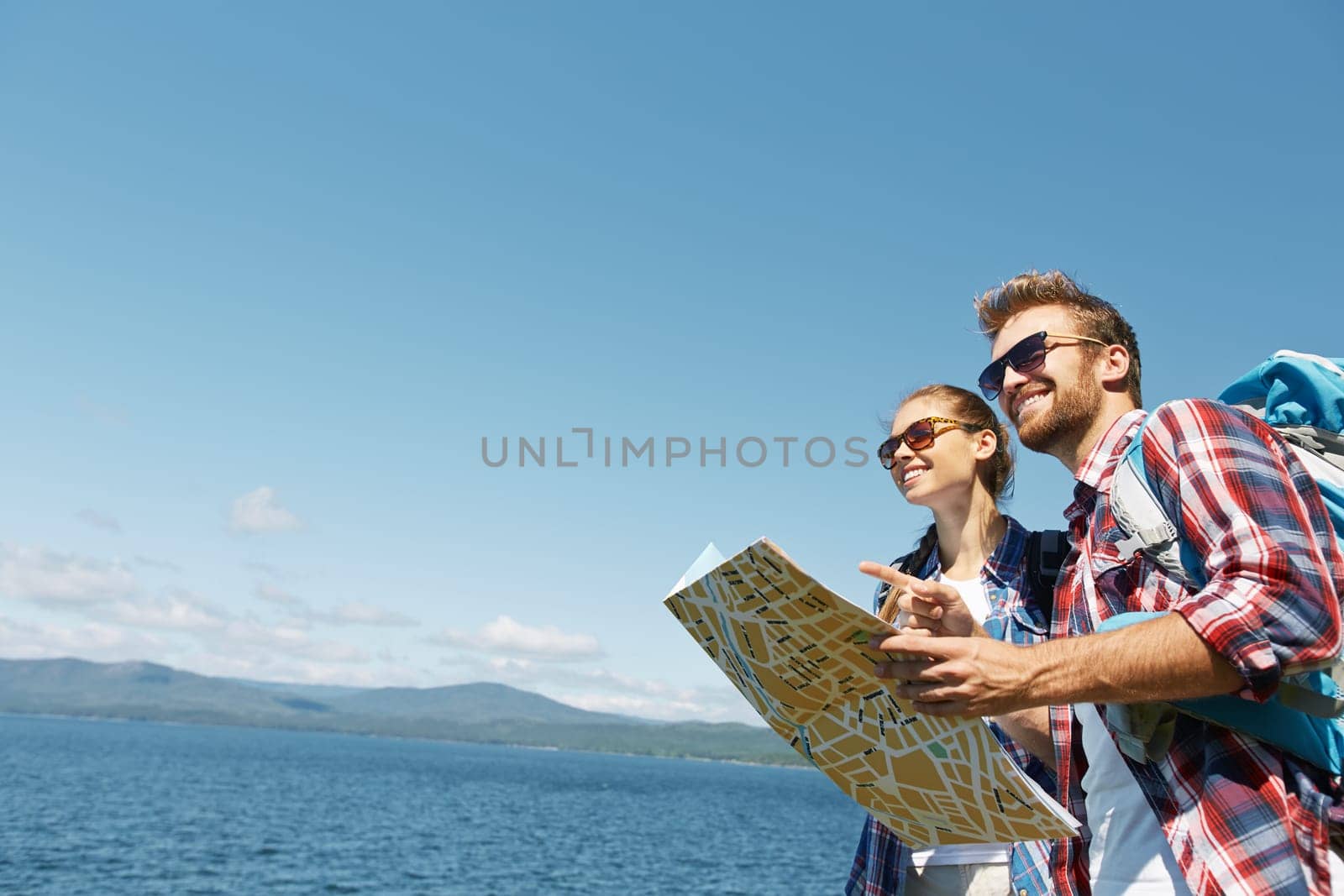 Amorous hikers with map on background of the sea