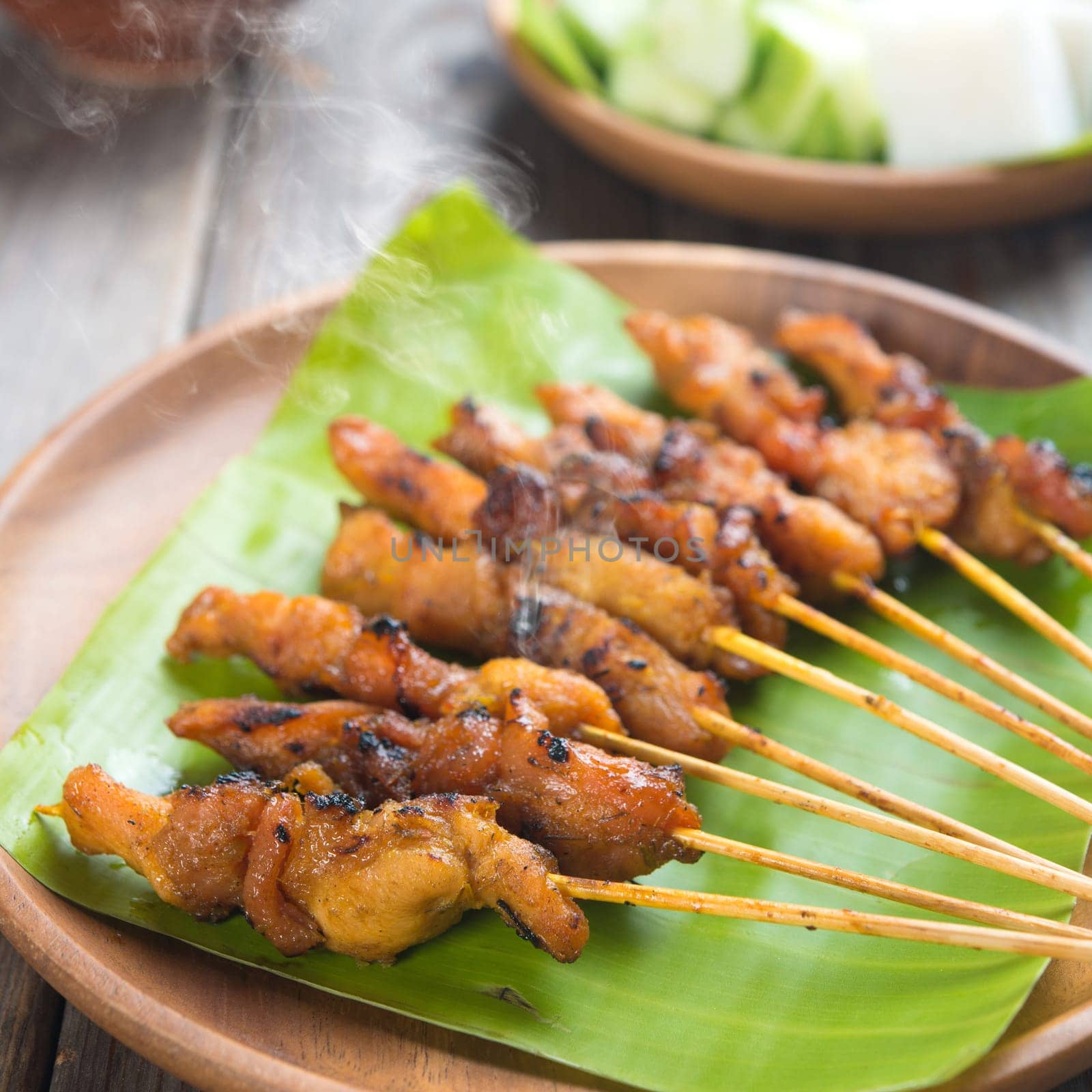 Yummy chicken sate or satay, skewered and grilled meat, served with peanut sauce. Fresh cooked with steamed and smoke. Hot and spicy Asian dish.