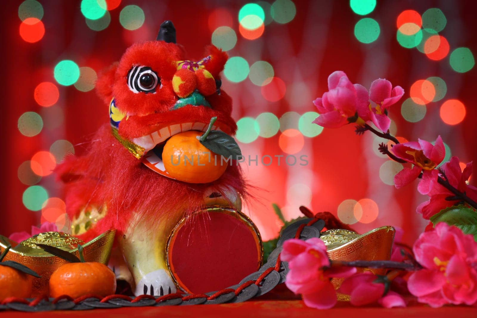 Chinese new year festival decorations, miniature dancing lion and mandarin orange, on glitter red background.