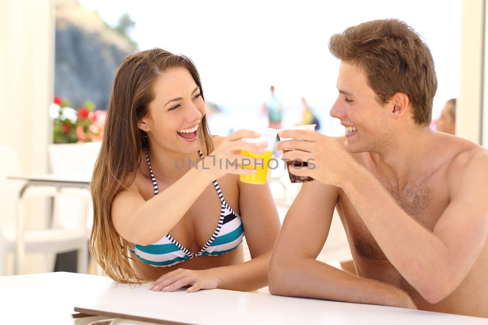 Friends toasting in summer vacation in a restaurant terrace on the beach