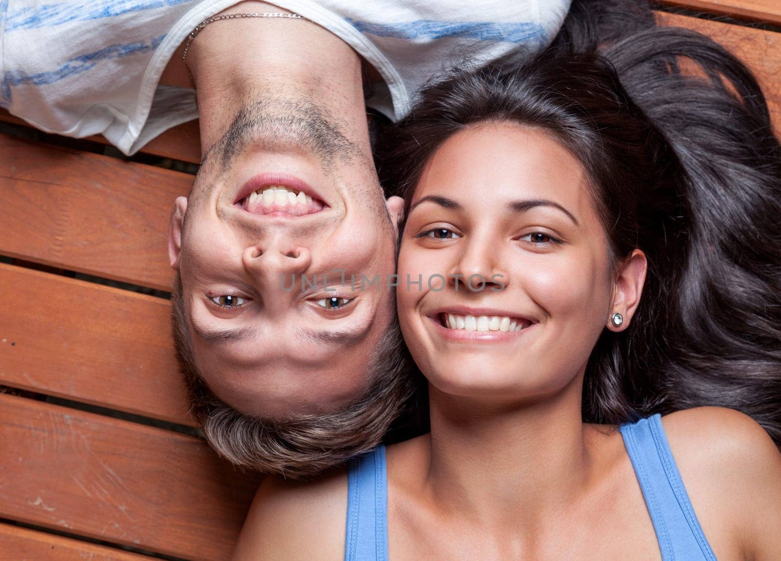 Happy young couple lying head to head on a wooden floor