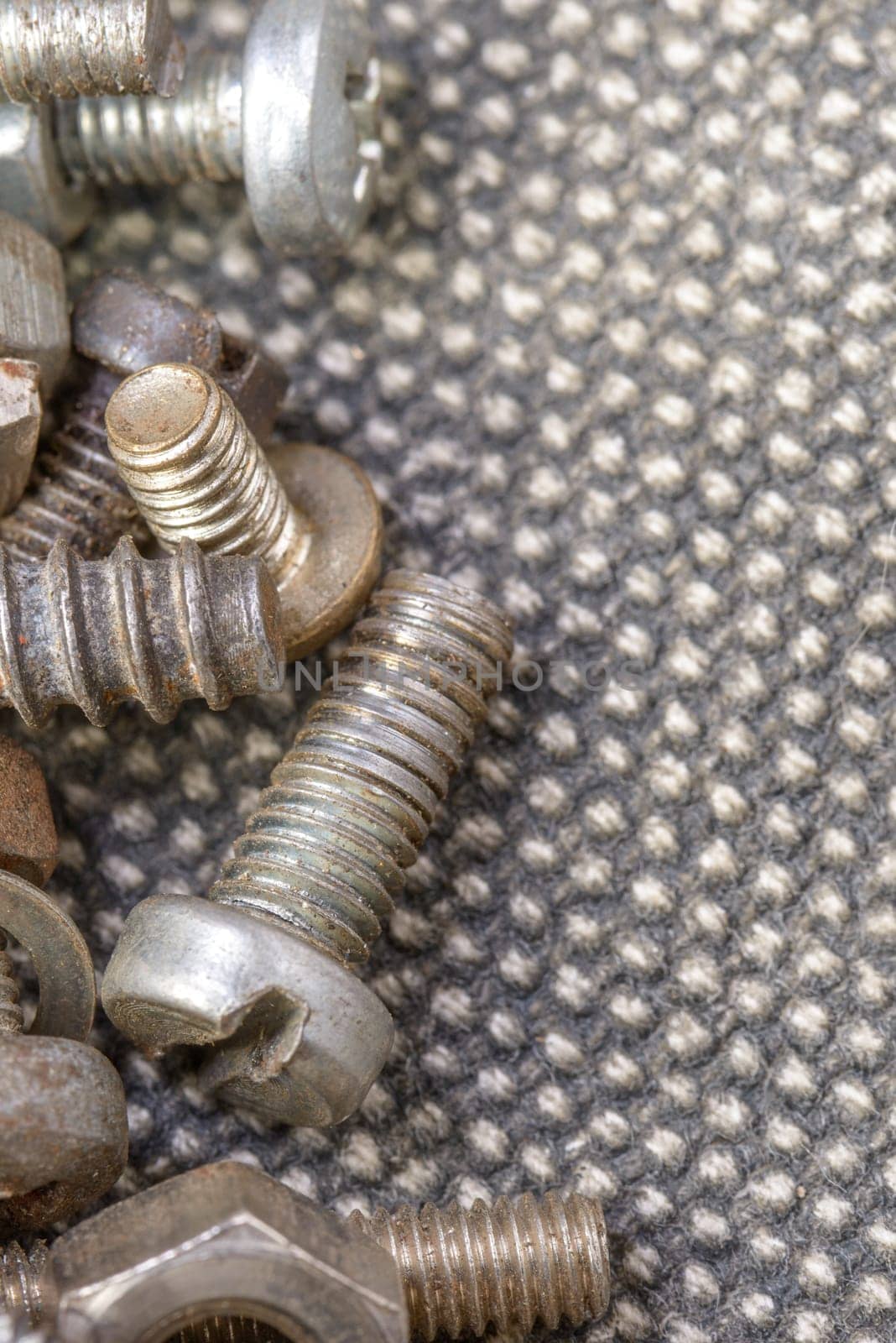 Several old screws on a grey texile background