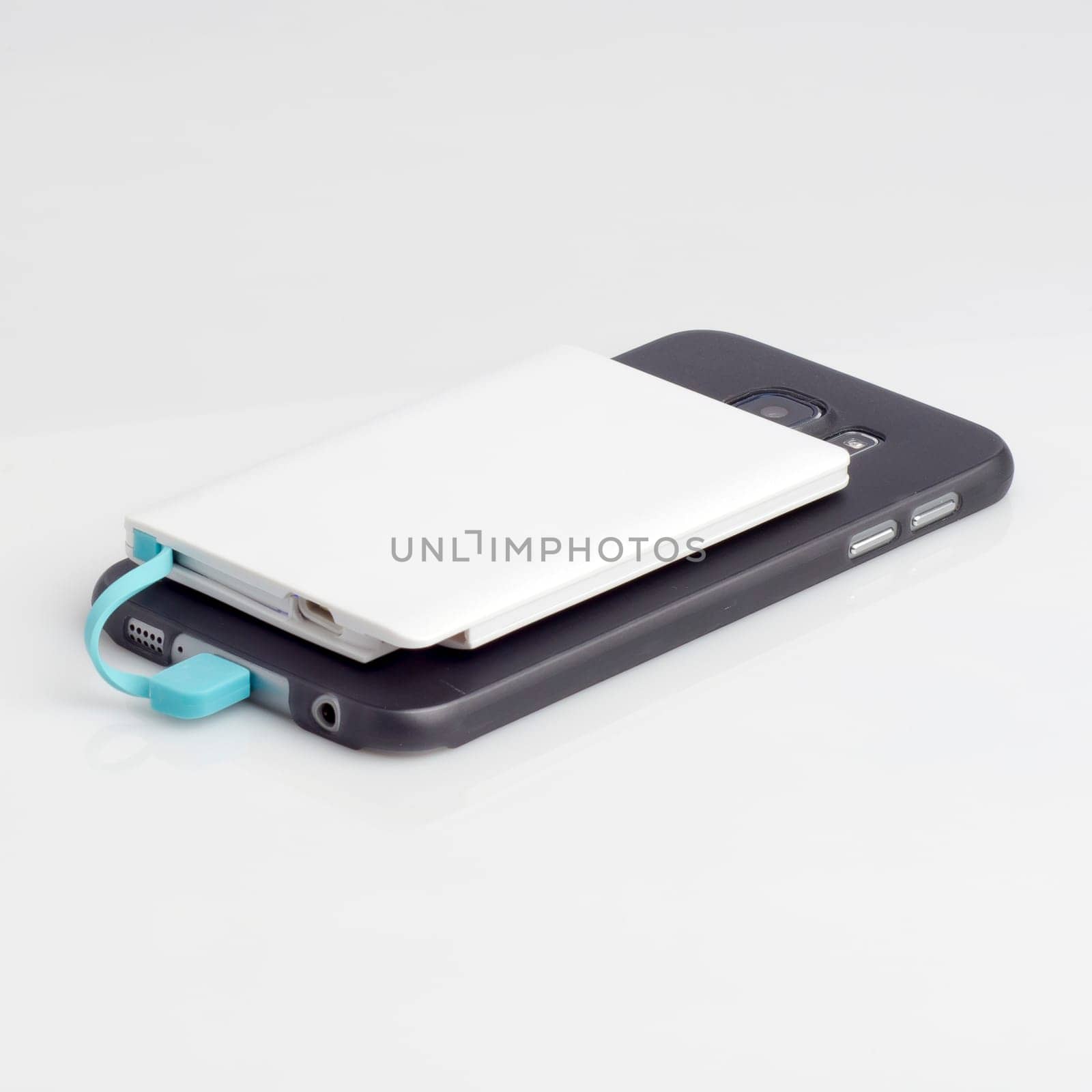 Charging a smartphone from powerbank on white table