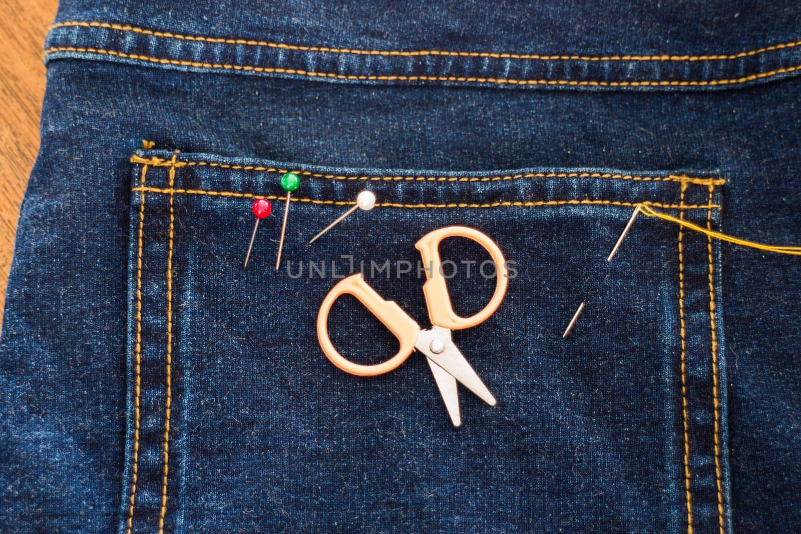 Needle with a thread through the jean, stock photo