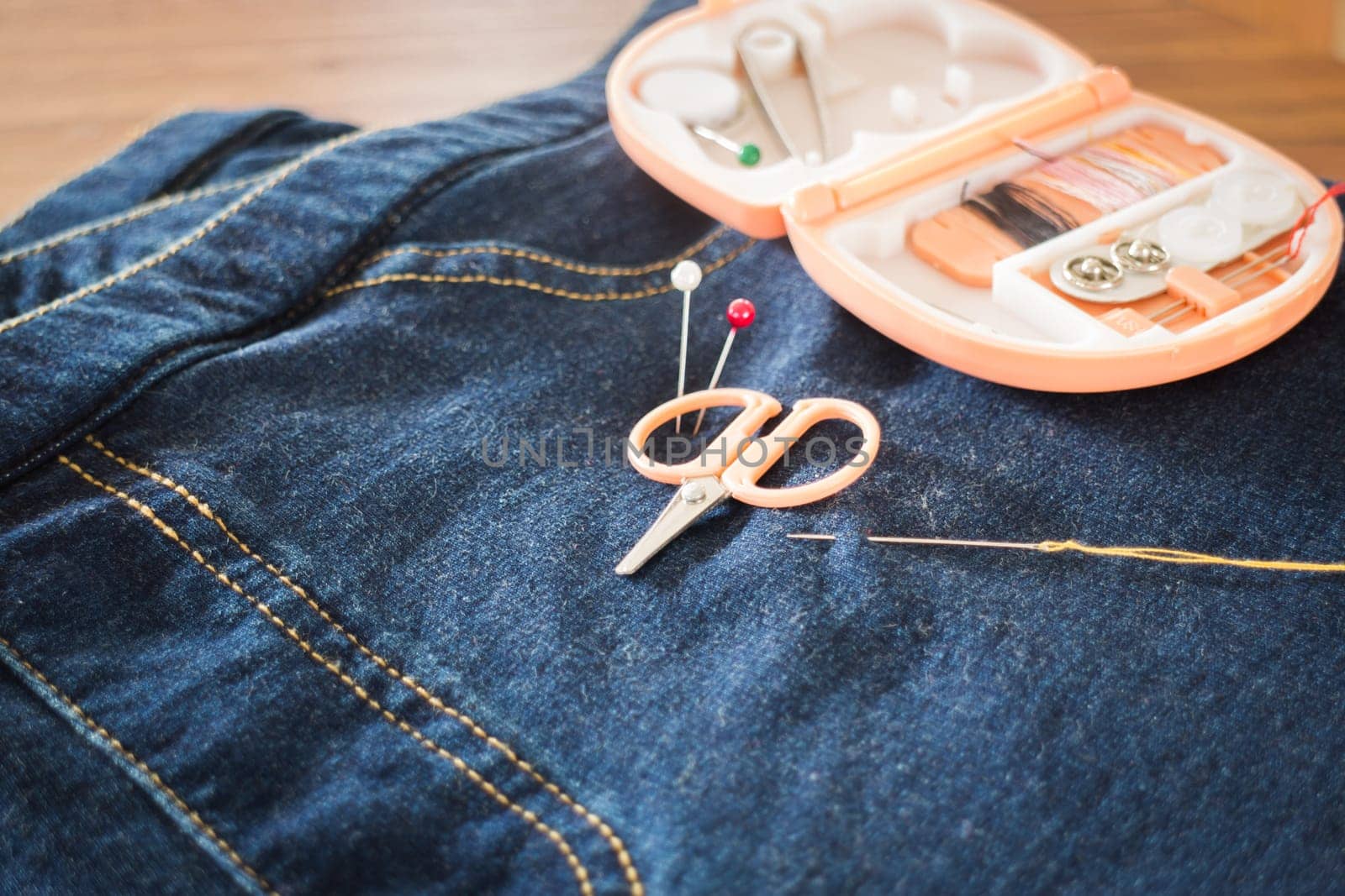 Needle with a thread through the jean, stock photo