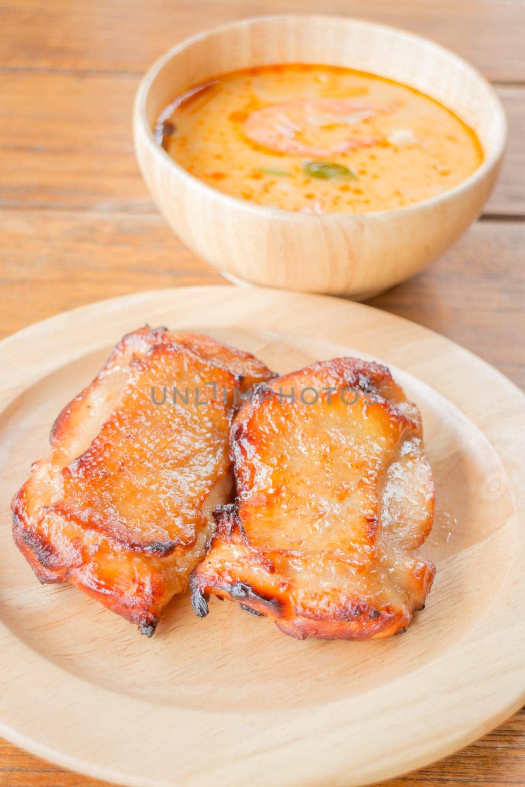 Chicken steak and spicy soup on wooden table, stock photo