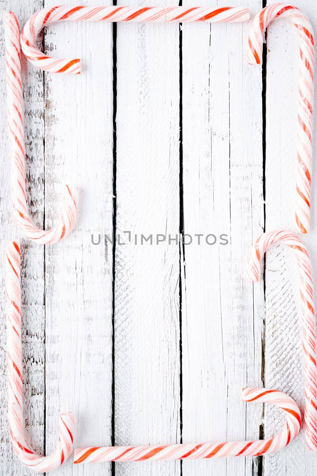 Several candy canes making frame over wooden background