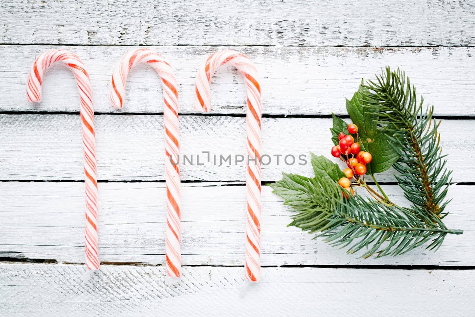 Cane candies, conifer and guelder over wooden background