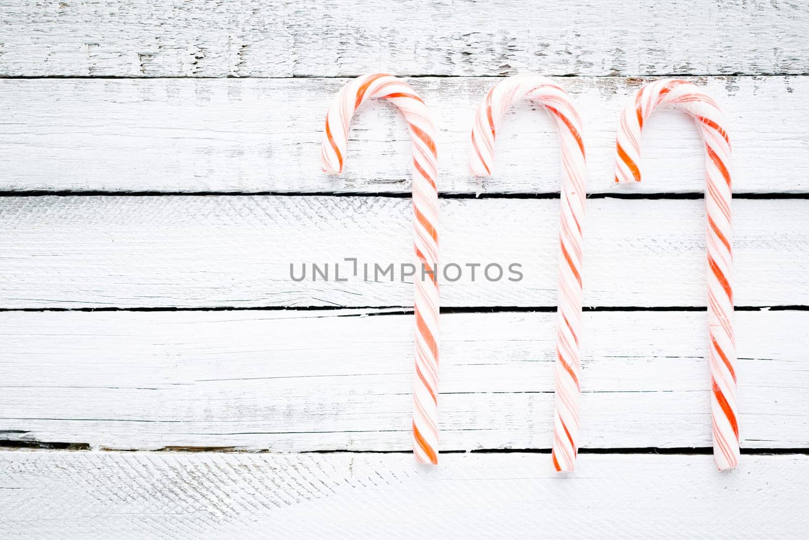 Three candy canes over wooden background