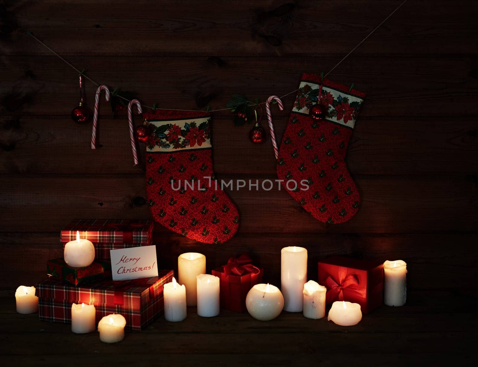 Christmas socks, sugar canes, toy bubbles, burning candles and giftboxes on wooden background