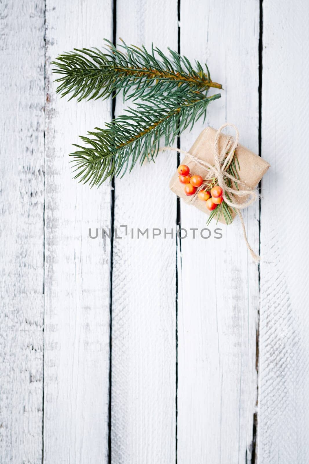 Small giftbox and two conifer branches over wooden background