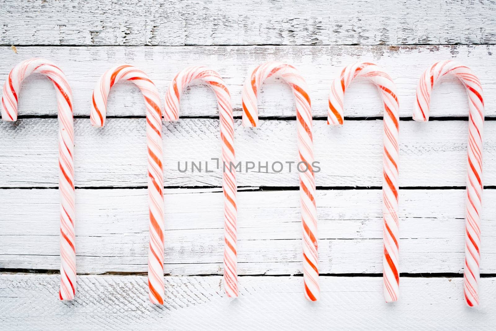 Striped candy canes over wooden background