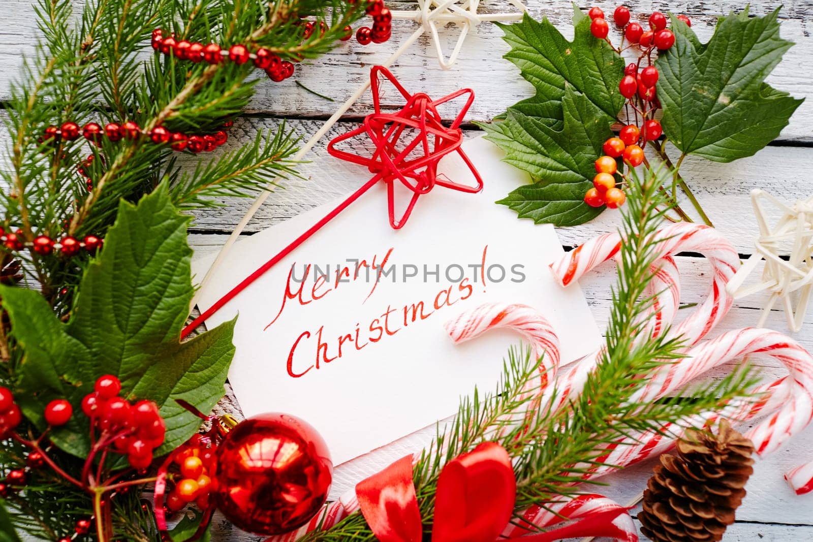 Chrismas decorations and greeting card with regards on white wooden background