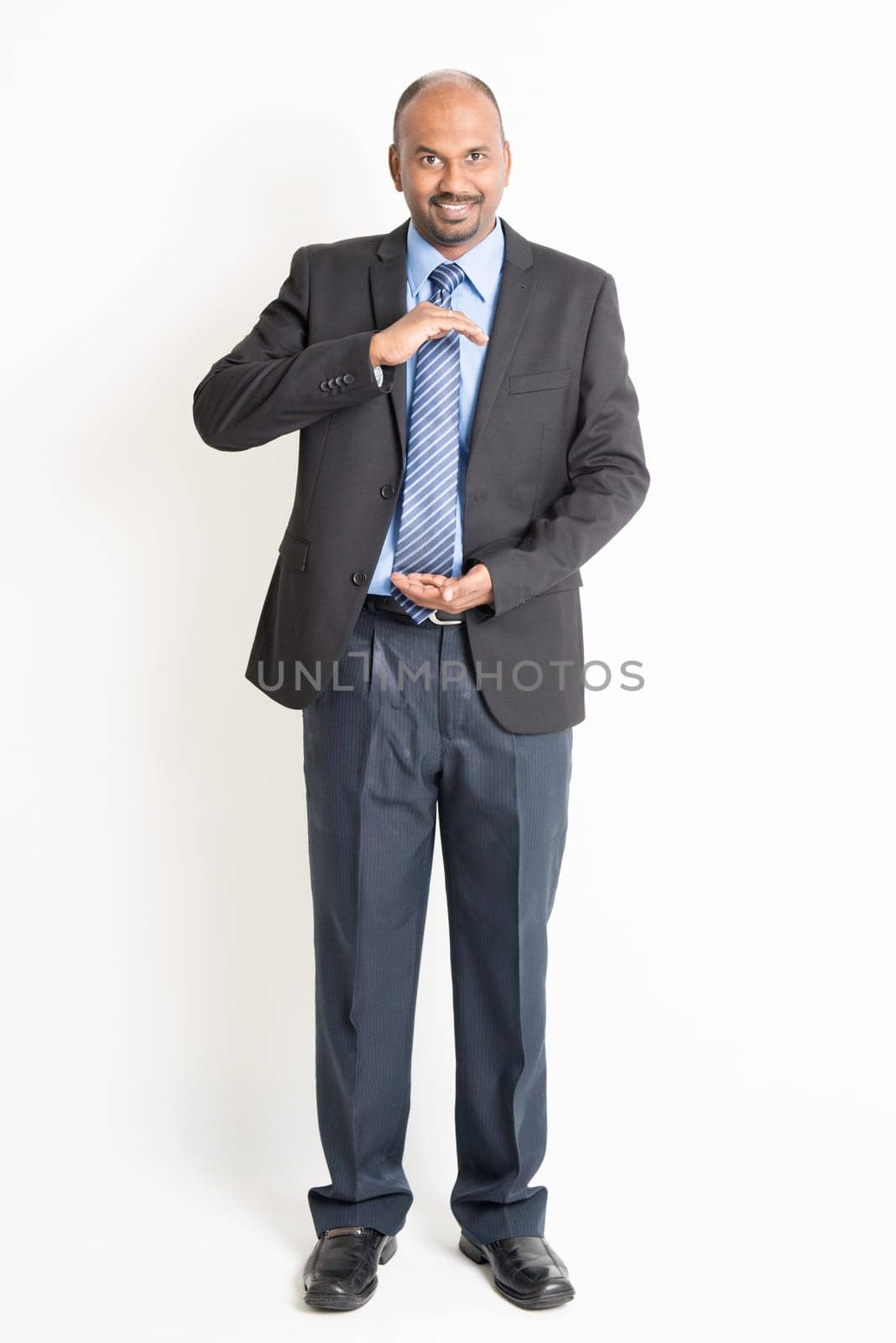 Full body mature Indian business man with cupped hands as if holding something, standing on plain background.