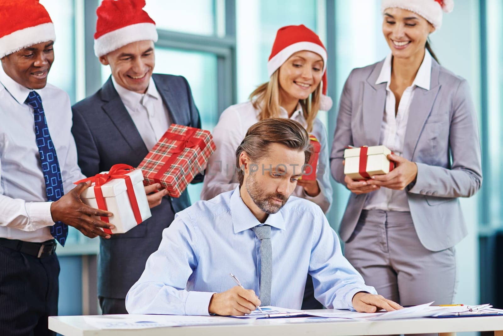 Serious businessman working with papers with his partners holding giftboxes behind