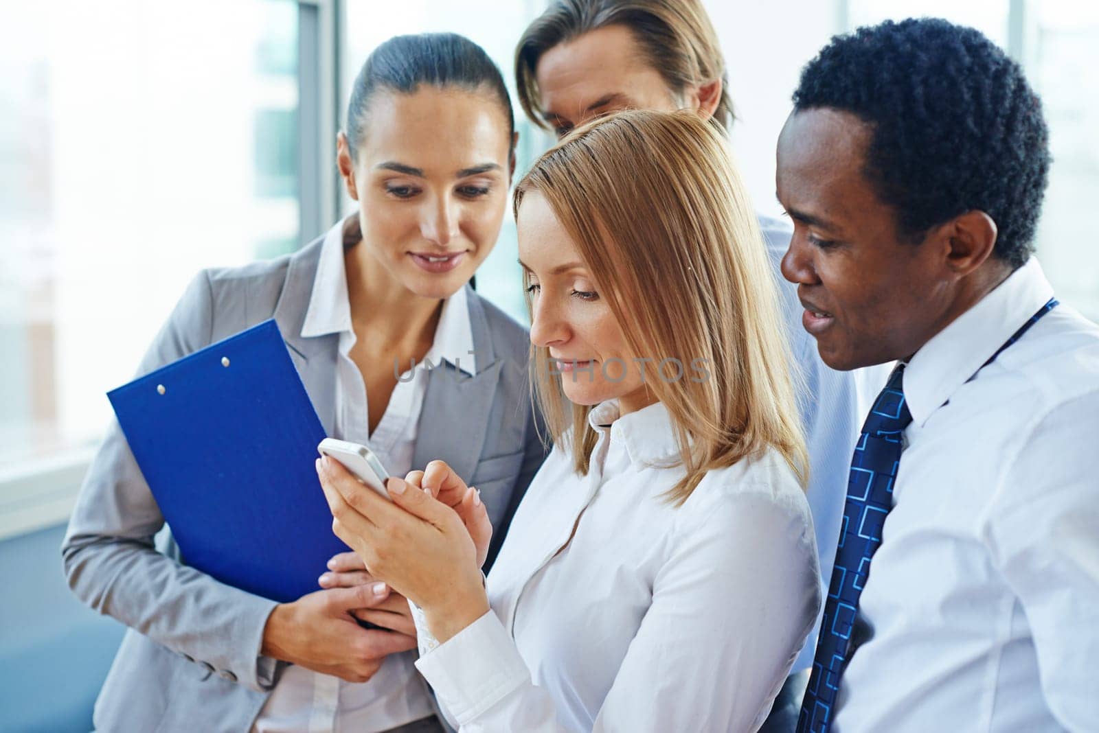 Businesswoman with cellphone and her colleagues reading sms