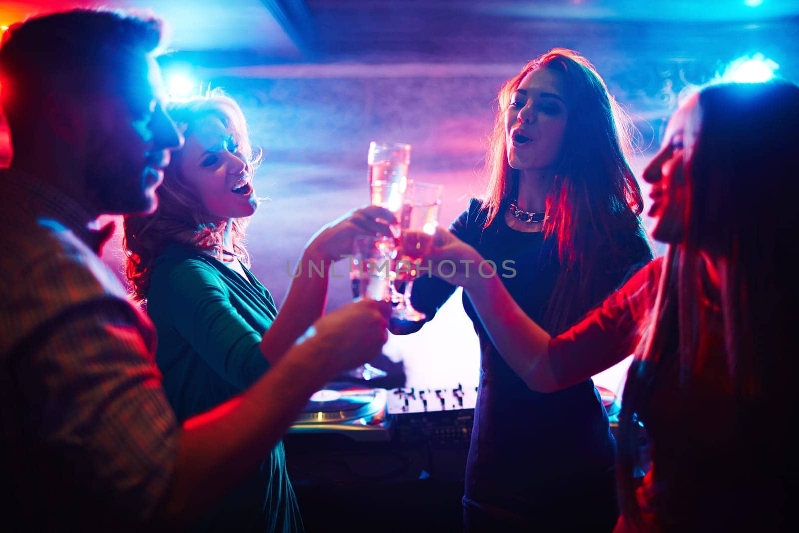 Cheerful friends toasting at party in night club