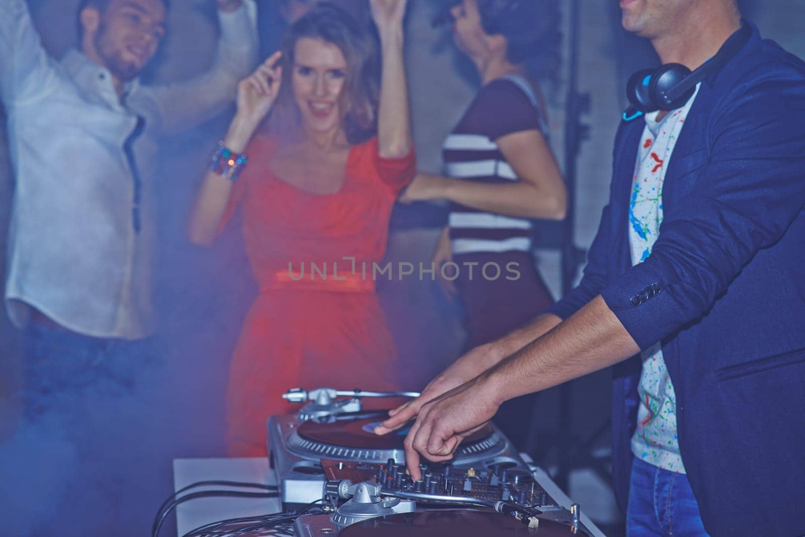 Male deejay adjusting sound on background of dancing friends