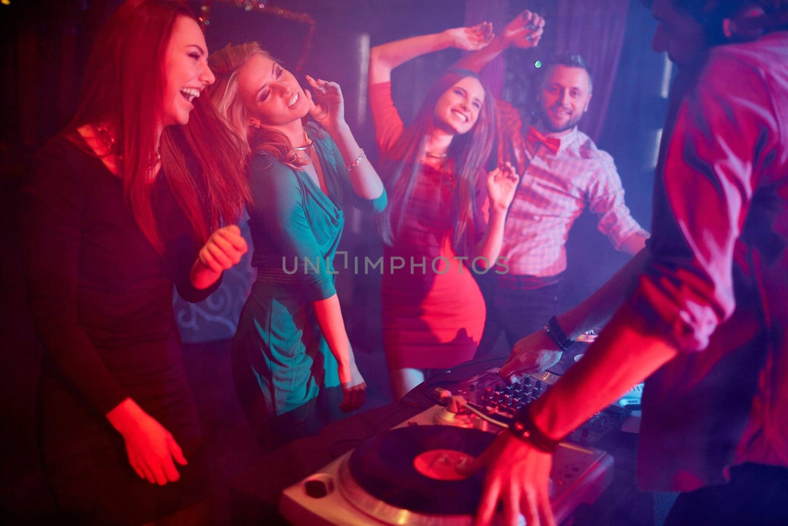 Cute girls dancing by turntables and dj adjusting sound