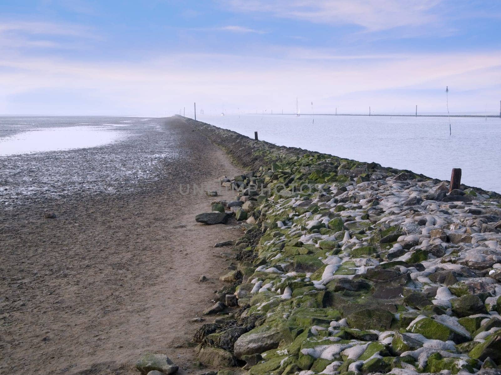 View over a rocky protective wall towards the horizon at the harbour entrance of Bensersiel / East Frisia in Germany