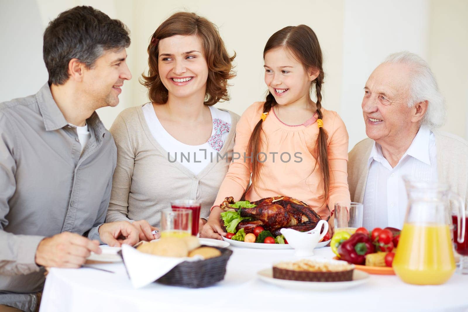 Happy family at Thanksgiving table going to eat roasted turkey held by cute girl