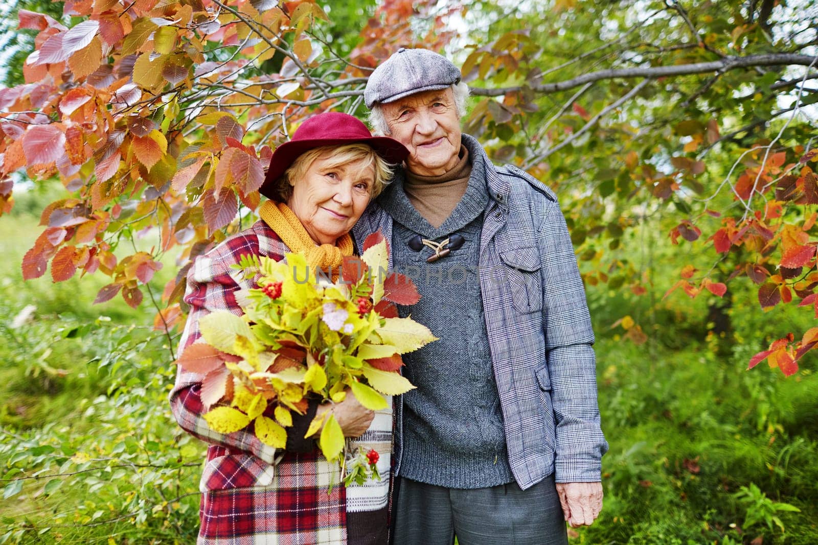 Happy senior couple under branch looking at camera
