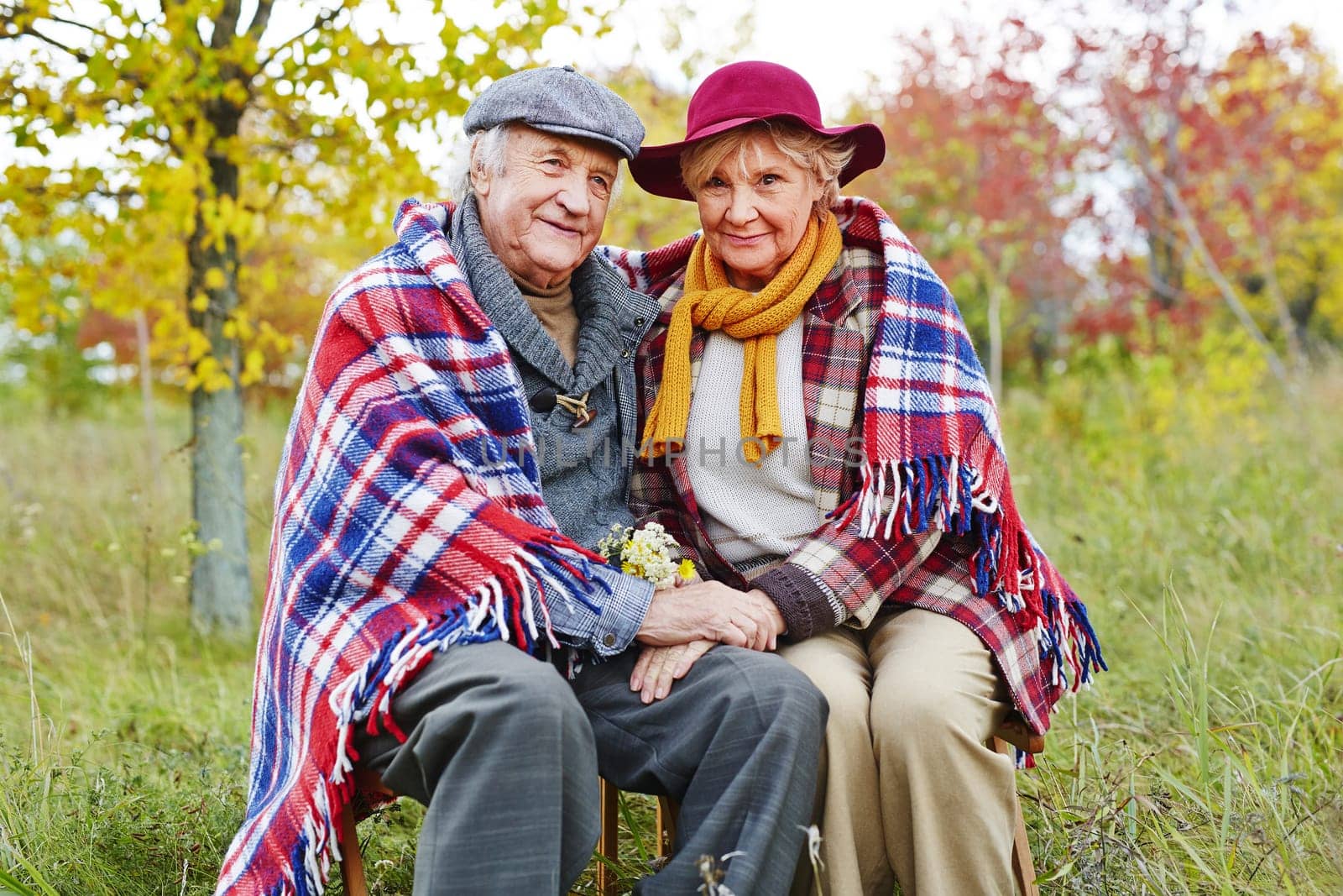 Retired man and woman in warm clothes resting outdoors in autumn