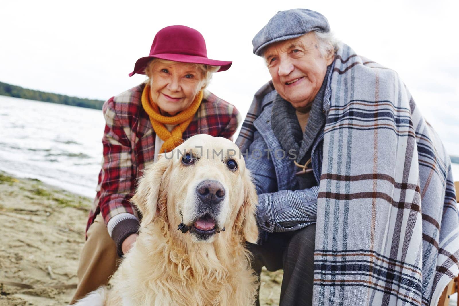Retired couple and their pet relaxing by seaside on weekend