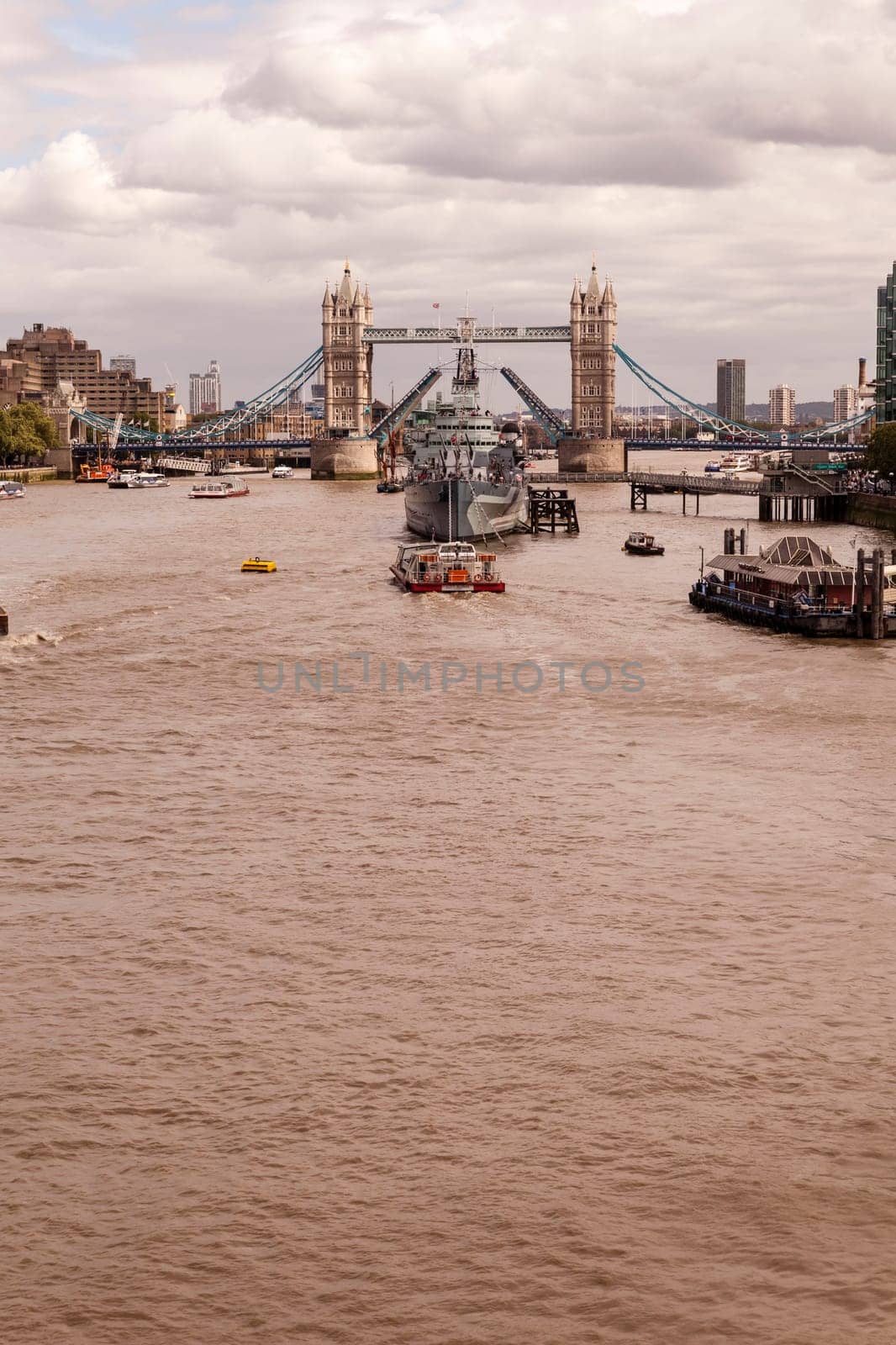 London, United Kingdom - August 04, 2015: Decommissioned battleship HMS Belfast in River Thames moored between London Bridge City Pier and one of Britain’s most famous landmarks, The Tower Bridge.