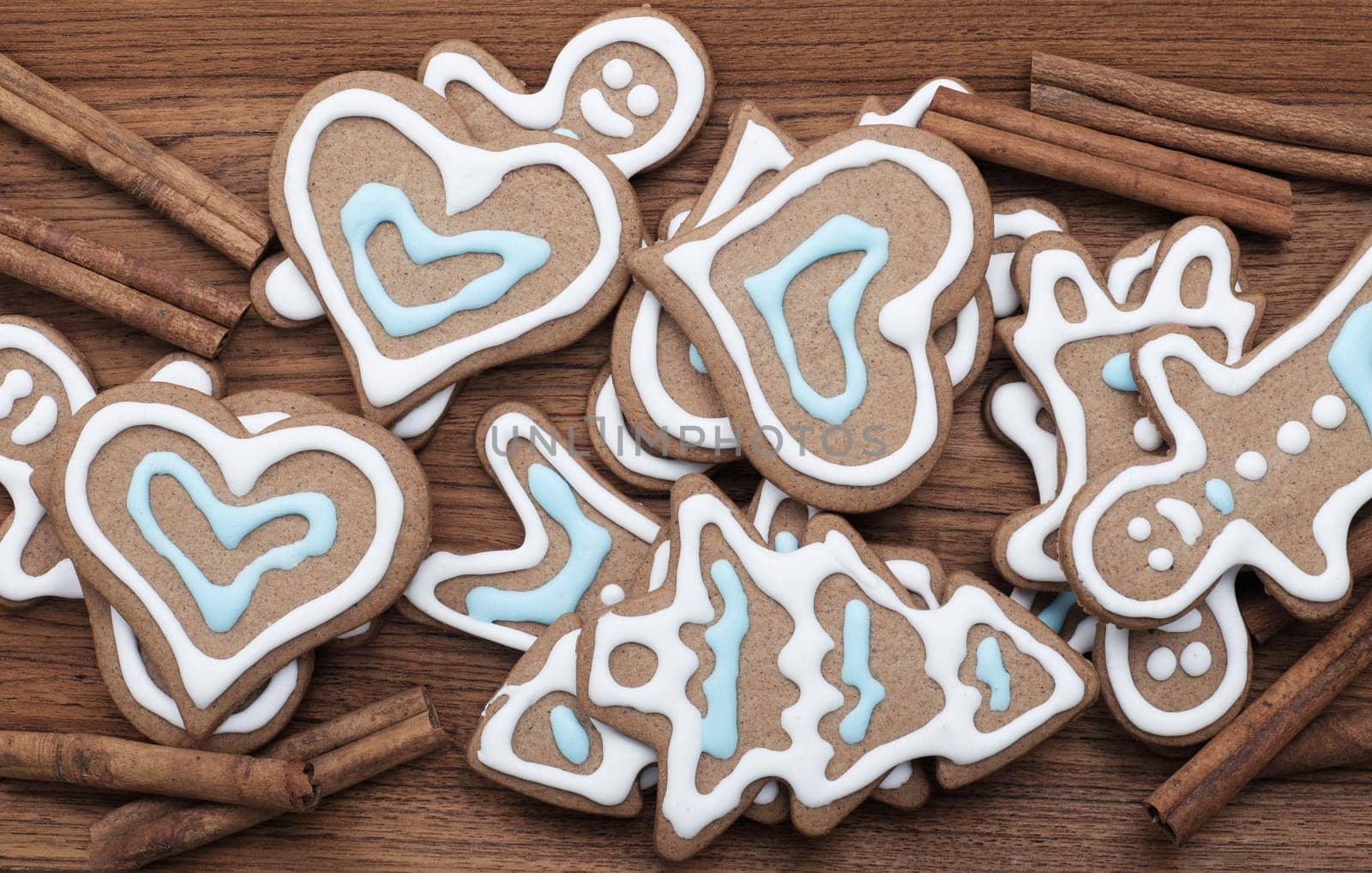 Decorated gingerbread cookies with cinnamon sticks on a wooden background