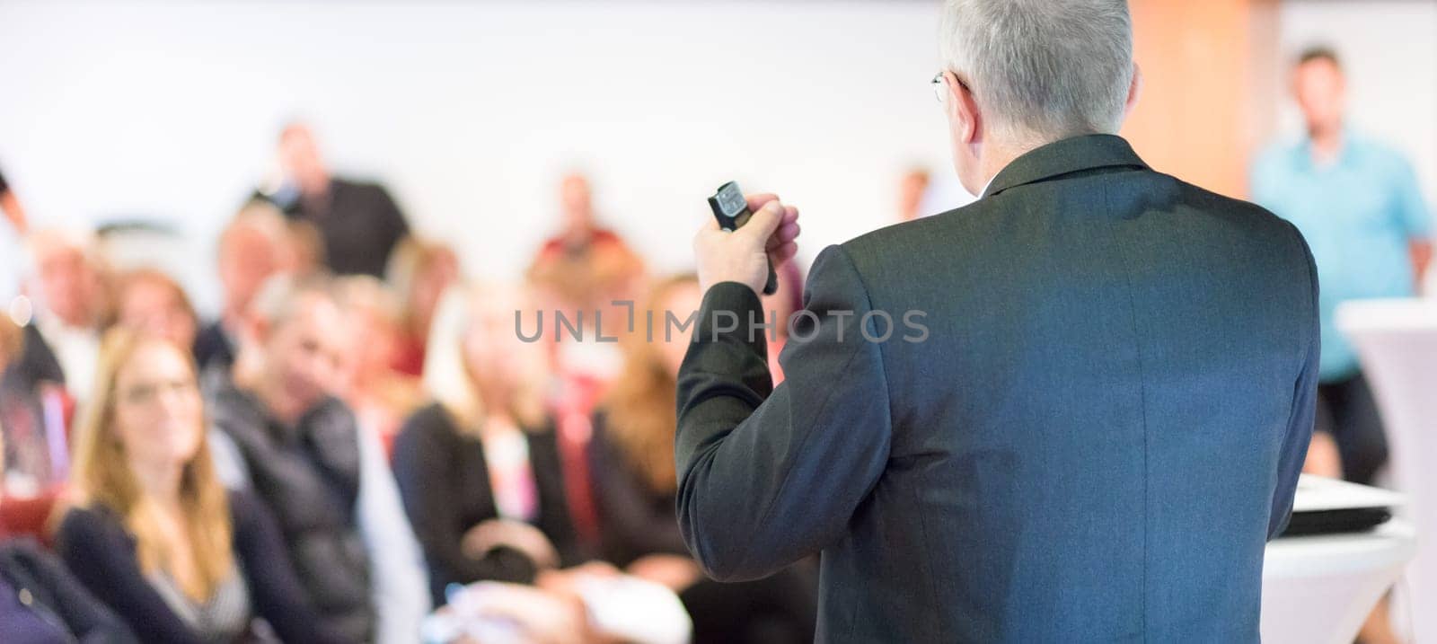 Speaker at Business Conference with Public Presentations. Audience at the conference hall. Entrepreneurship club. Rear view. Horisontal composition. Background blur.