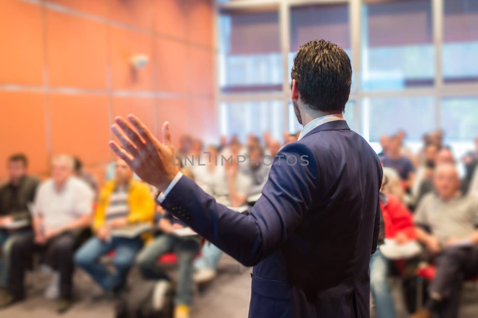 Speaker at Business Conference with Public Presentations. Audience at the conference hall. Entrepreneurship club. Rear view. Horisontal composition. Background blur.