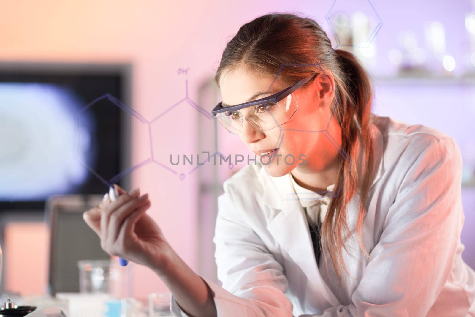 Life science researcher working in laboratory. Portrait of a confident female health care professional in his working environment reviewing structural chemical formula written on a glass board.