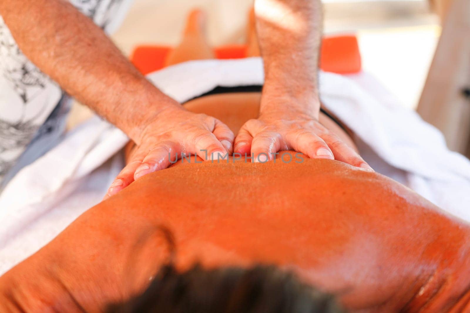 Massage therapist working with suntanned beautiful woman at  beach resort