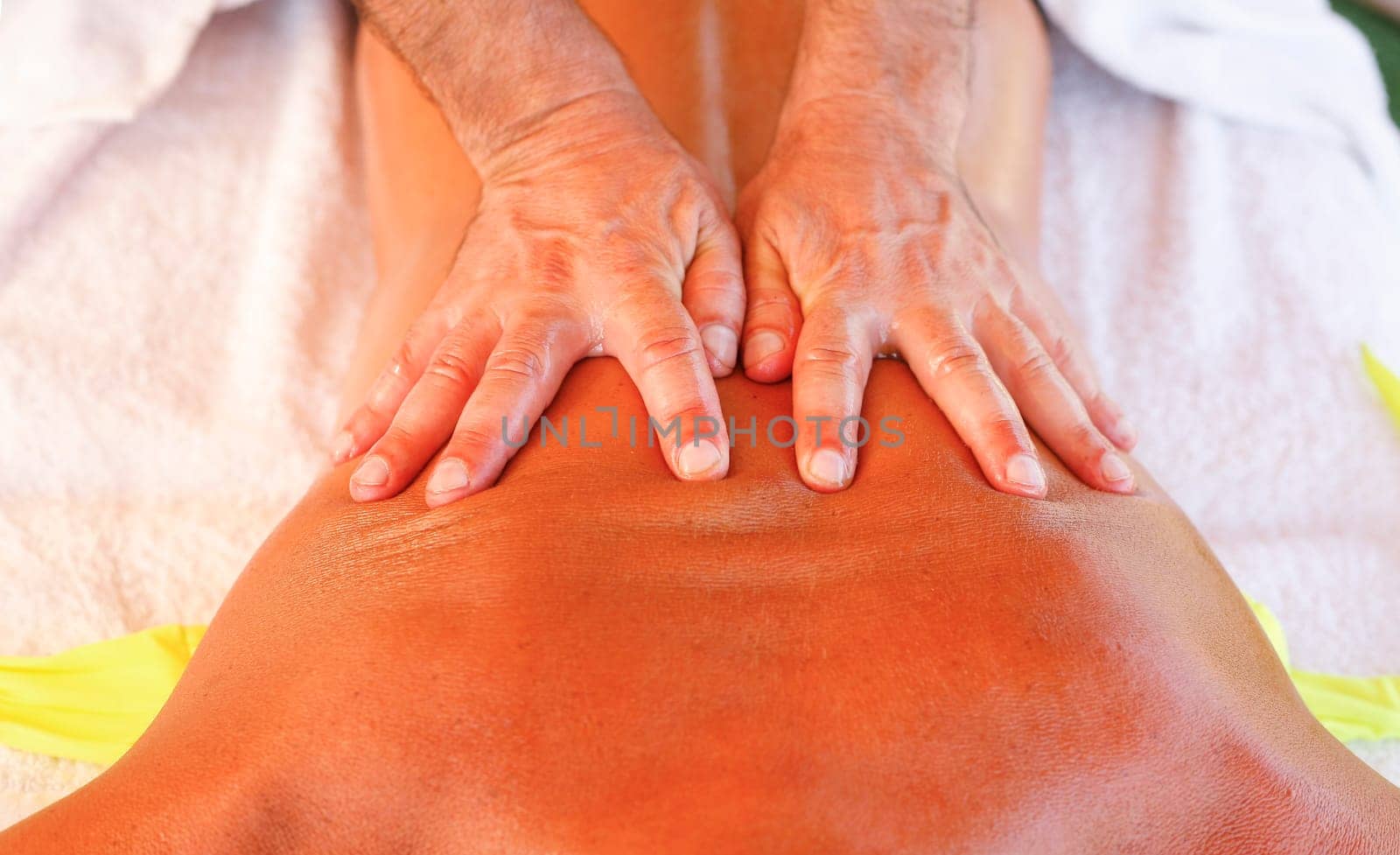 Massage therapist working with suntanned beautiful woman at  beach resort