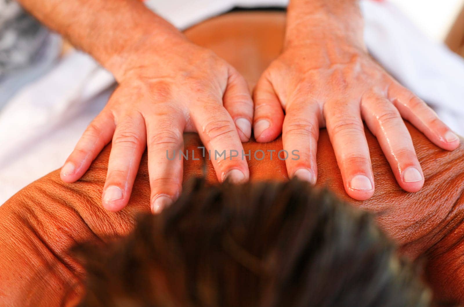 Massage therapist working with suntanned beautiful woman at  beach resort