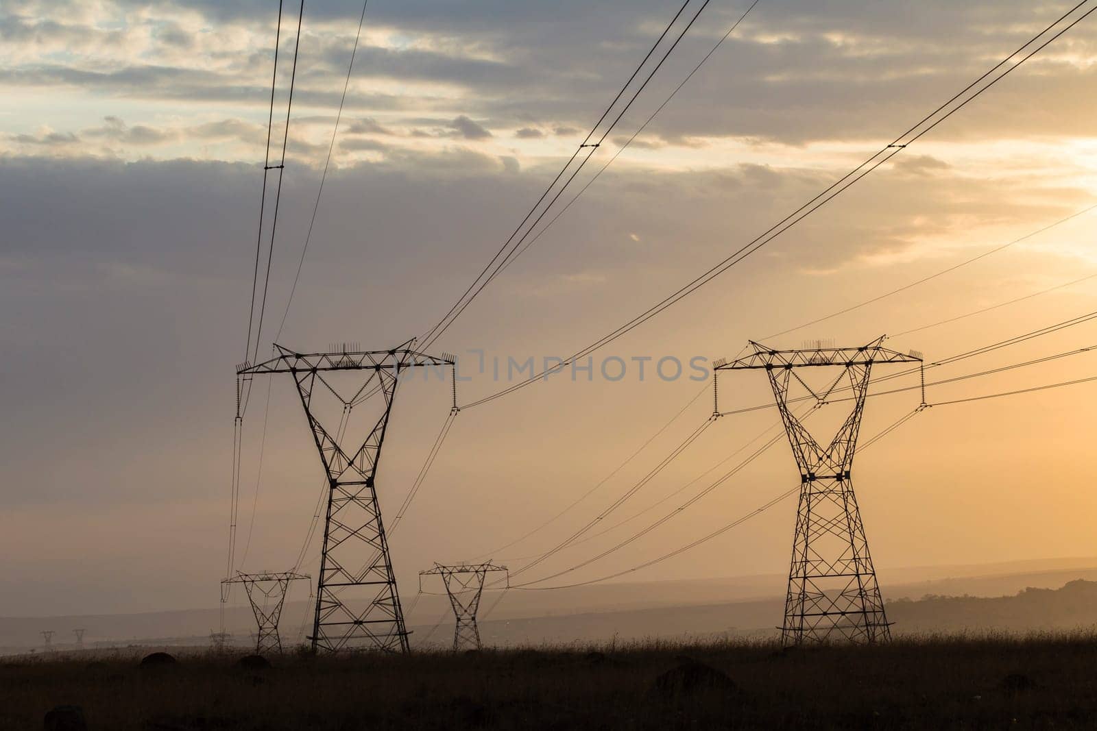 Powerlines electrical cables tower structures stretch over rural countryside