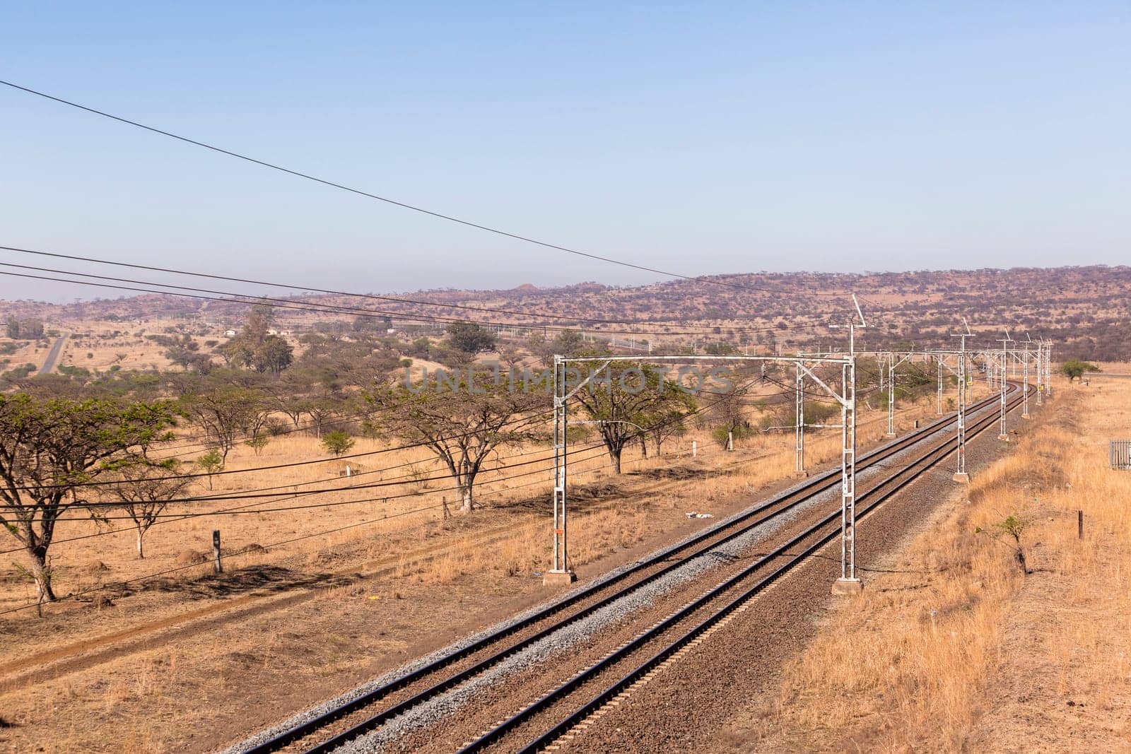 Railway train tracks line travel through dry season rural landscape