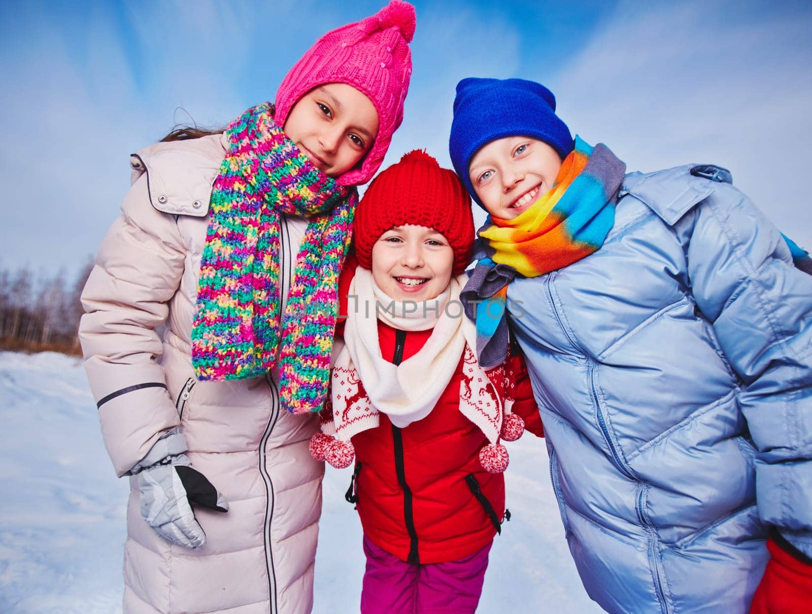 Joyful kids in winterwear looking at camera outdoors