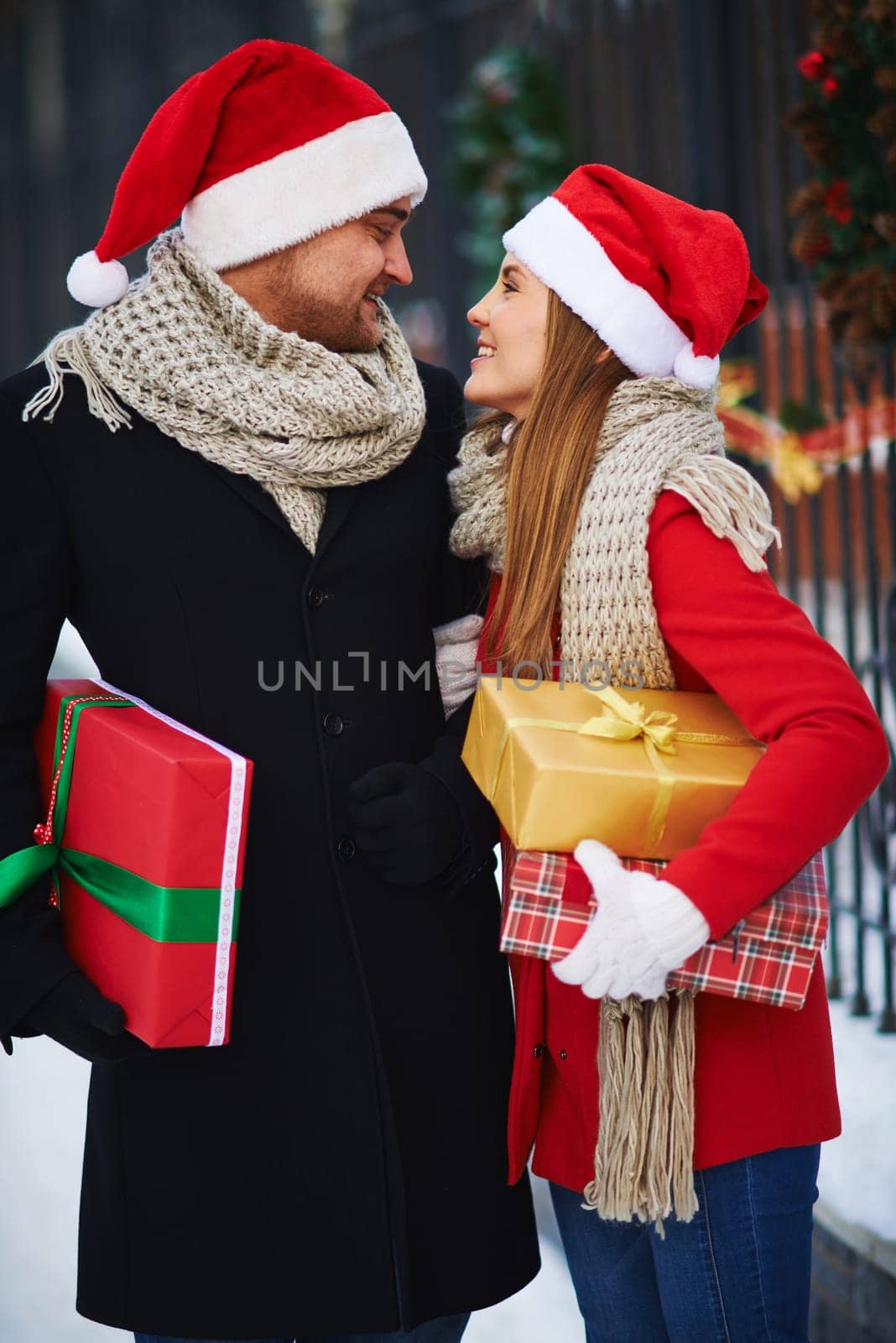 Romantic dates in Santa caps looking at one another on Christmas eve