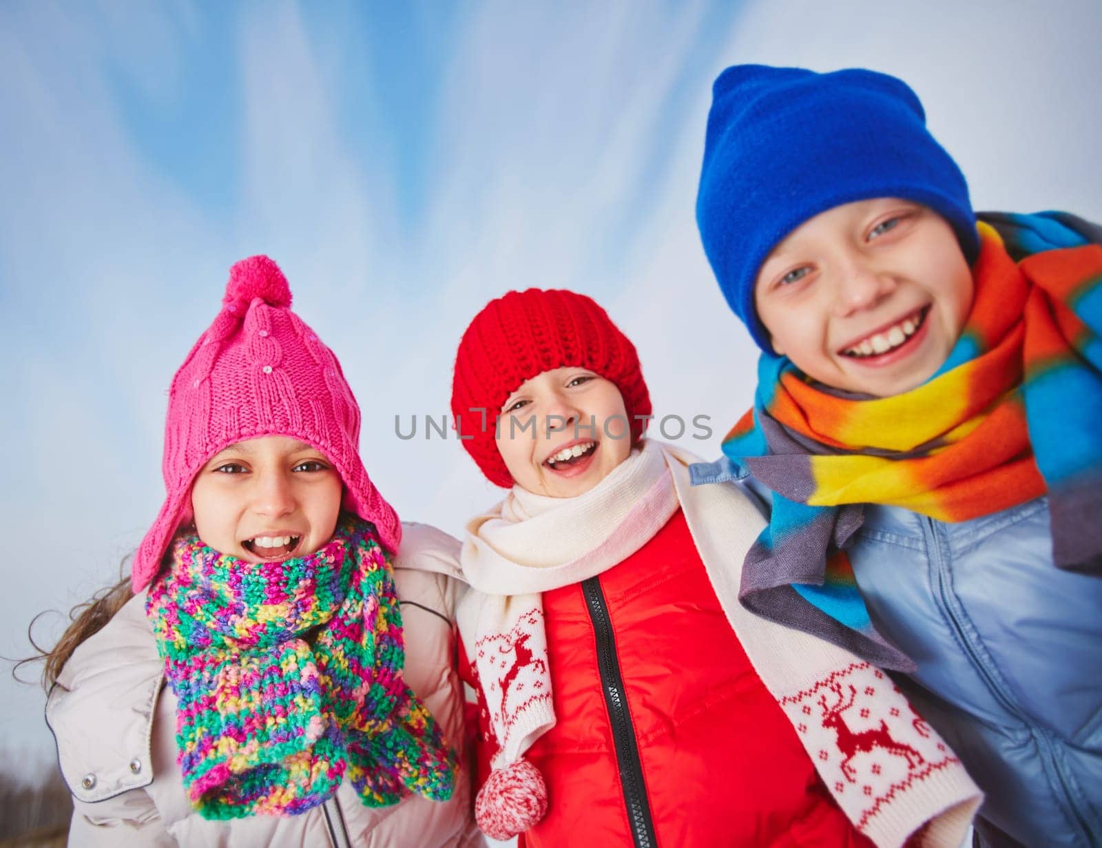 Joyful kids in winterwear looking at camera with smiles