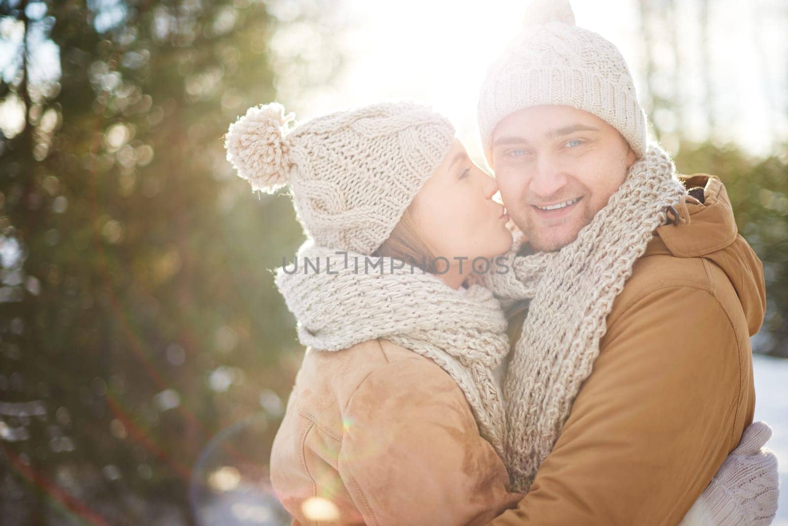 Young woman kissing her boyfriend in winter outside