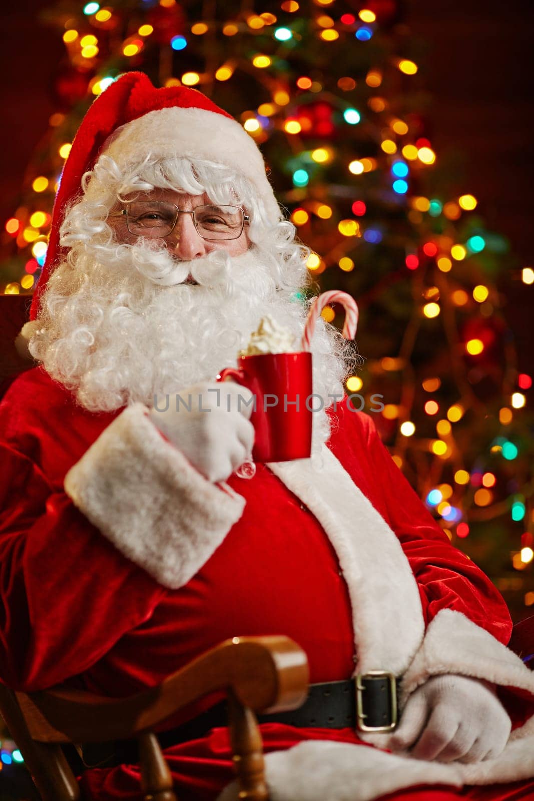 Santa Claus with cup of latte on background of Christmas tree