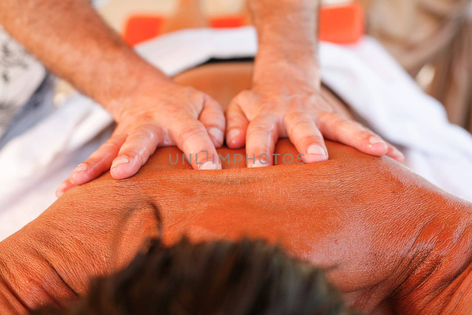 Massage therapist working with suntanned beautiful woman at  beach resort