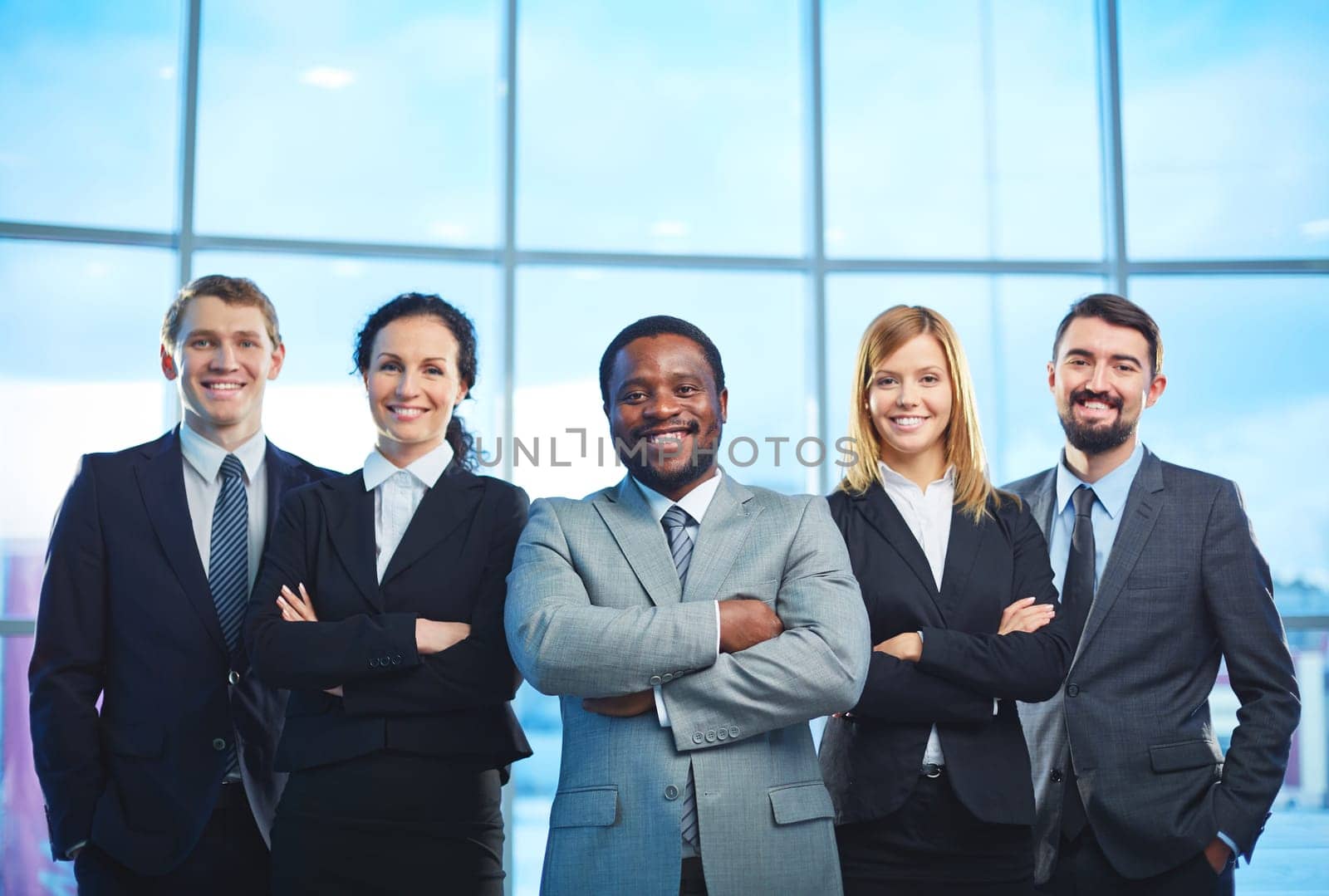 Group of contemporary business partners in formalwear looking at camera with smiles
